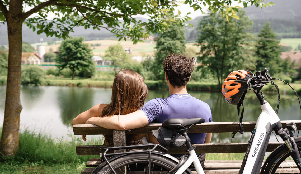 Paar auf dem Fahrrad Ebike unterwegs an einem See am Rain im ELztal entlang bei grüner Wiese